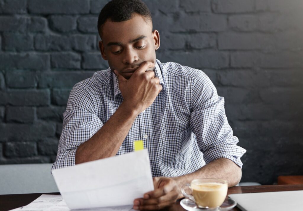 Homem com camisa azul e a mão no queijo consultando tudo o que um mei precisa