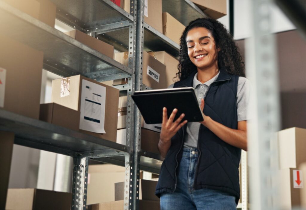 mulher sorridente com tablet organizando estoque.